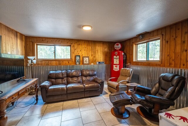 living area with light tile patterned flooring, a textured ceiling, and wood walls