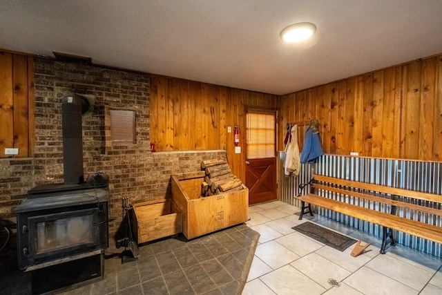 miscellaneous room featuring wooden walls, tile patterned flooring, and a wood stove