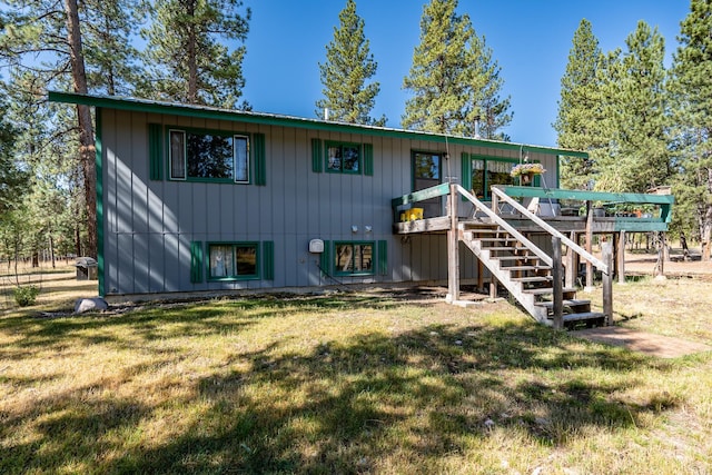 back of house with stairs, a yard, and a deck