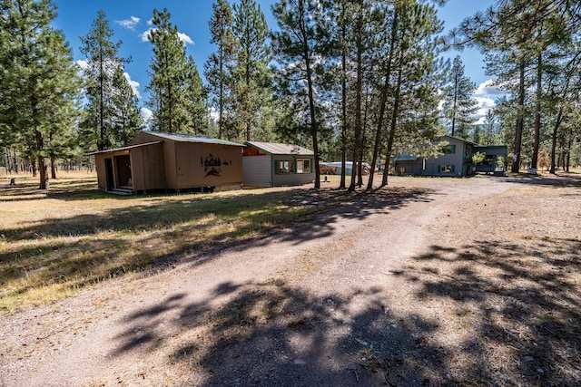 exterior space featuring metal roof, an outbuilding, an outdoor structure, and dirt driveway