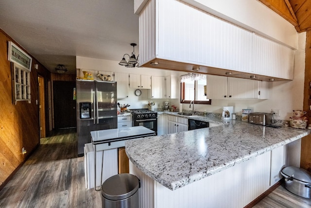 kitchen with a sink, black appliances, a peninsula, dark wood-style floors, and an inviting chandelier