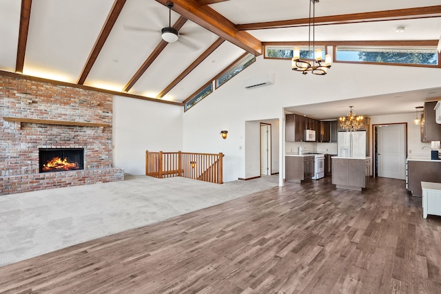 unfurnished living room with ceiling fan with notable chandelier, high vaulted ceiling, beam ceiling, dark carpet, and a brick fireplace