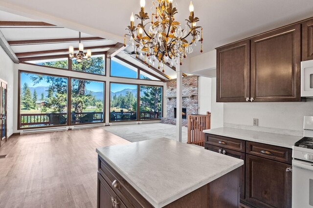 548 W Village Dr, Bigfork, MT 59911 - kitchen with a chandelier, white appliances, beamed ceiling, dark brown cabinetry, and a brick fireplace
