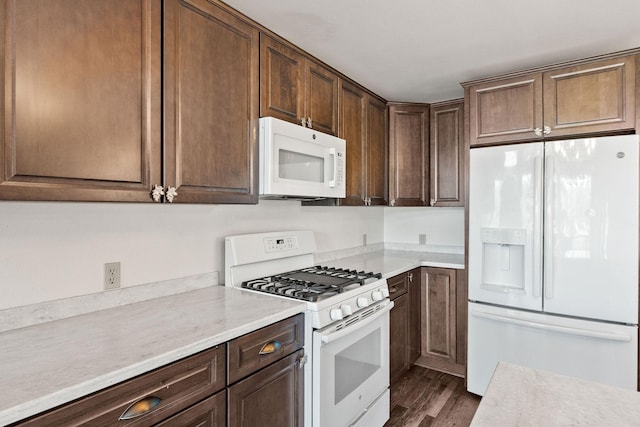 kitchen with white appliances, light countertops, dark brown cabinetry, and dark wood-style flooring