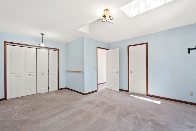 unfurnished bedroom with baseboards, a closet, a skylight, and light colored carpet