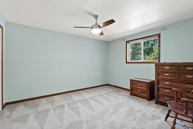 unfurnished bedroom with light colored carpet, ceiling fan, a textured ceiling, and baseboards