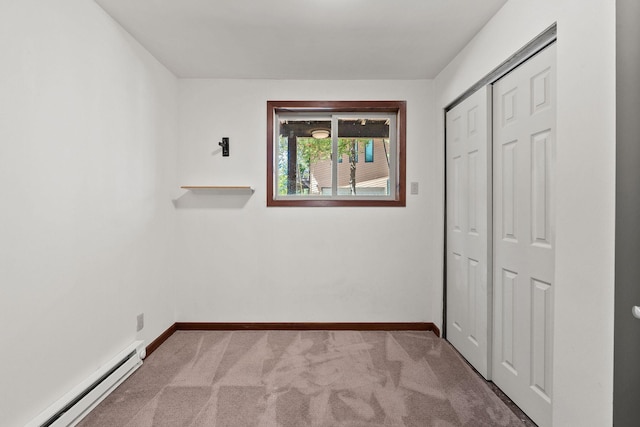 unfurnished bedroom with a baseboard heating unit, a closet, light colored carpet, and baseboards