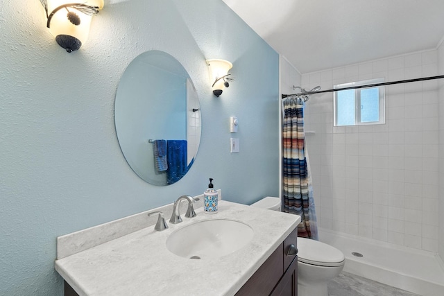 bathroom featuring toilet, a textured wall, a tile shower, and vanity