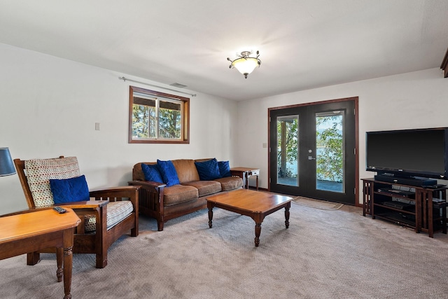 living room featuring a healthy amount of sunlight, light carpet, visible vents, and french doors