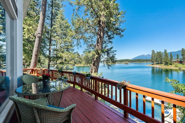 deck featuring outdoor dining space and a water and mountain view