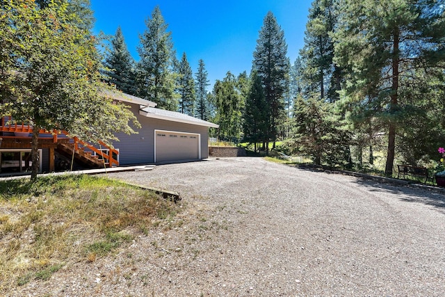 view of side of home featuring a garage and gravel driveway