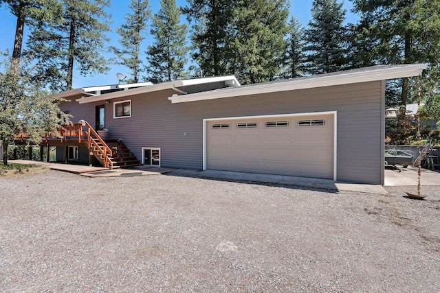 548 W Village Dr, Bigfork, MT 59911 - view of property exterior featuring stairway, a garage, a wooden deck, and dirt driveway
