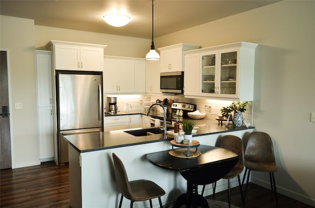 kitchen with stainless steel appliances, dark countertops, glass insert cabinets, white cabinets, and a peninsula