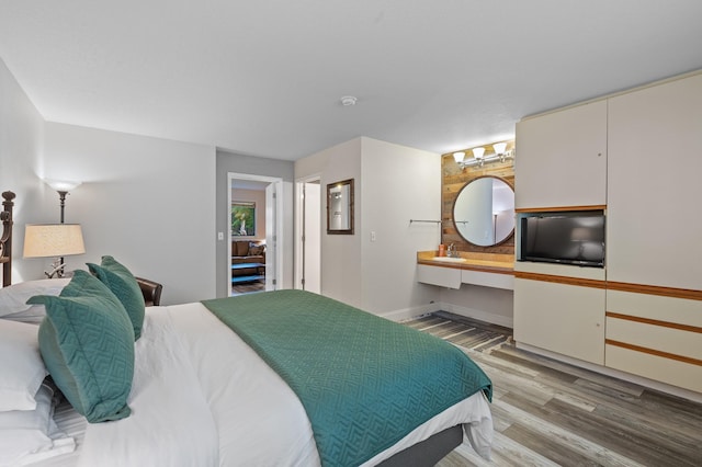 bedroom featuring wood finished floors, baseboards, and a sink