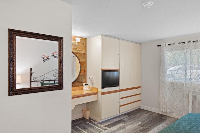 bedroom with light wood-type flooring, baseboards, and built in study area