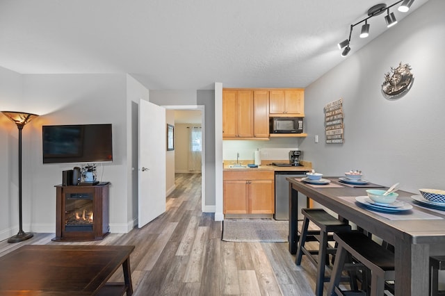 kitchen featuring stainless steel dishwasher, wood finished floors, black microwave, and a sink