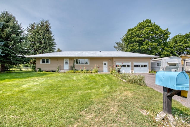 single story home featuring metal roof, aphalt driveway, an attached garage, and a front yard