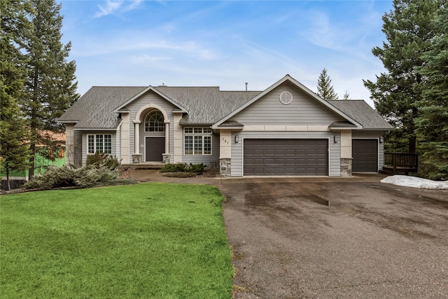 ranch-style house with driveway, stone siding, an attached garage, a front lawn, and a shingled roof