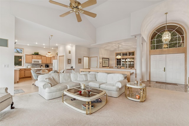 living room with light carpet, ceiling fan with notable chandelier, and high vaulted ceiling