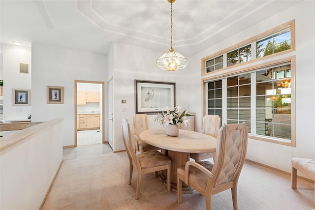 dining space featuring a healthy amount of sunlight, an inviting chandelier, and light colored carpet
