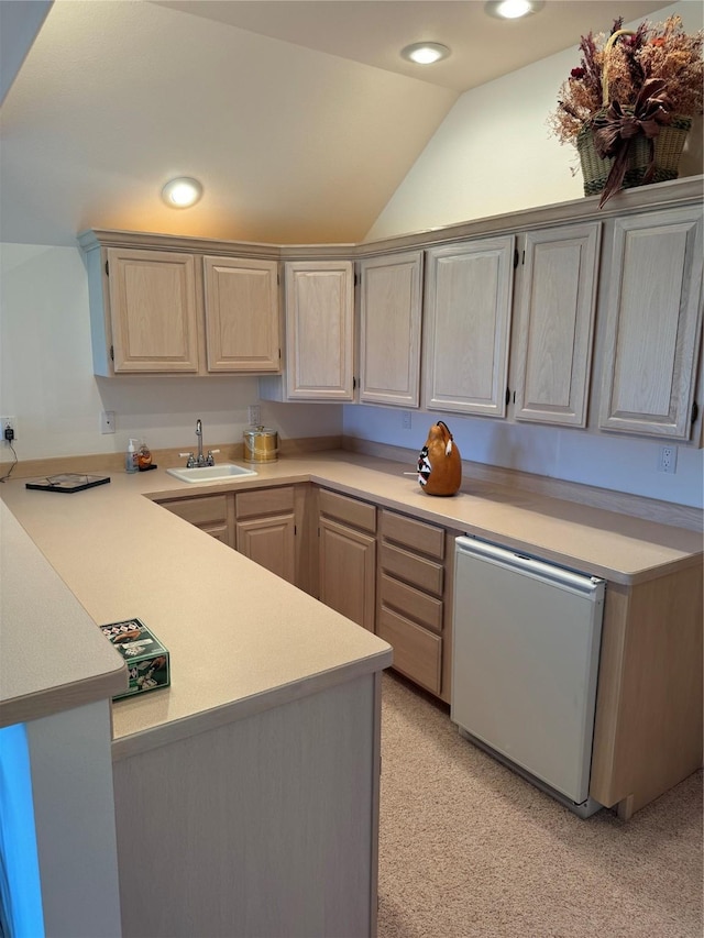 kitchen with dishwasher, vaulted ceiling, sink, and kitchen peninsula