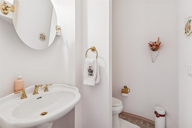 bathroom featuring baseboards, a sink, and toilet