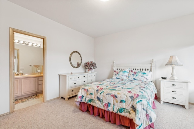 bedroom featuring baseboards, ensuite bathroom, and light colored carpet