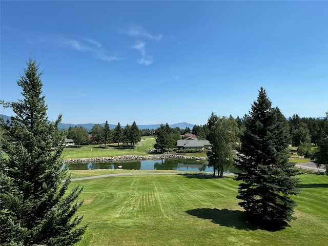 view of home's community with a water and mountain view and a yard