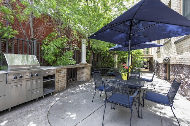 view of patio / terrace with grilling area, fence, outdoor dining space, and exterior kitchen