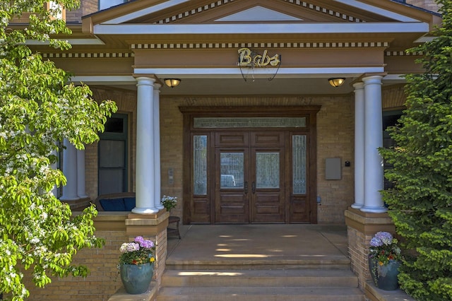 doorway to property with brick siding and a porch