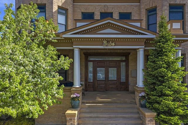 view of exterior entry with brick siding and a porch