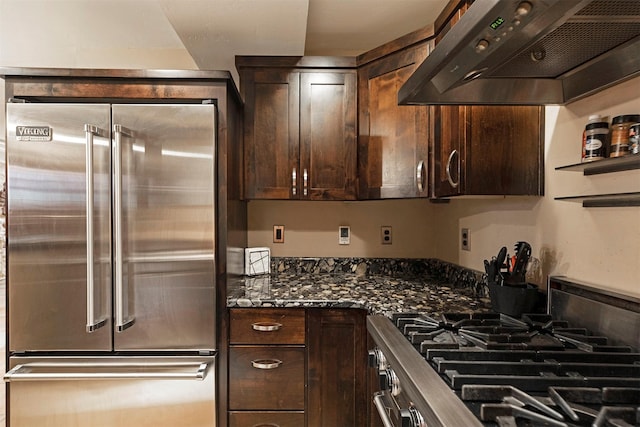 kitchen with dark stone counters, exhaust hood, dark brown cabinets, and stainless steel appliances