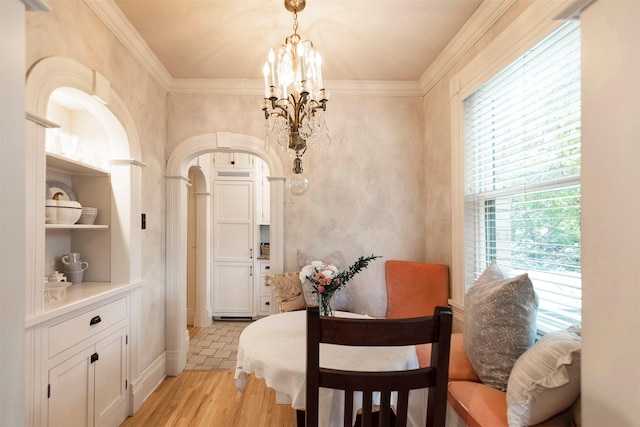 dining room with crown molding, light wood-style flooring, built in shelves, and a chandelier