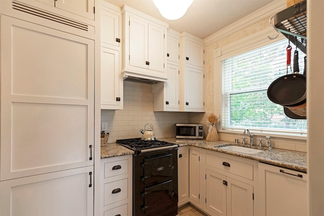 kitchen featuring black gas range oven, stainless steel microwave, dishwasher, decorative backsplash, and a sink