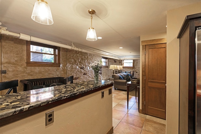 kitchen featuring hanging light fixtures, dark stone counters, and light tile patterned floors