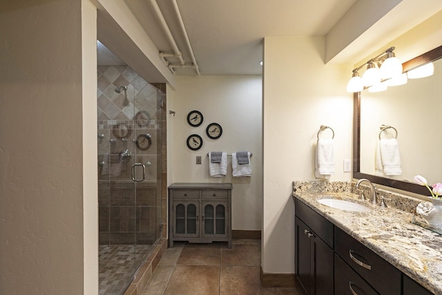 bathroom with baseboards, a stall shower, vanity, and tile patterned flooring