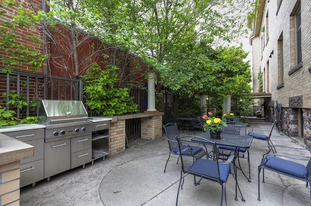 view of patio / terrace featuring grilling area, an outdoor kitchen, outdoor dining space, and fence