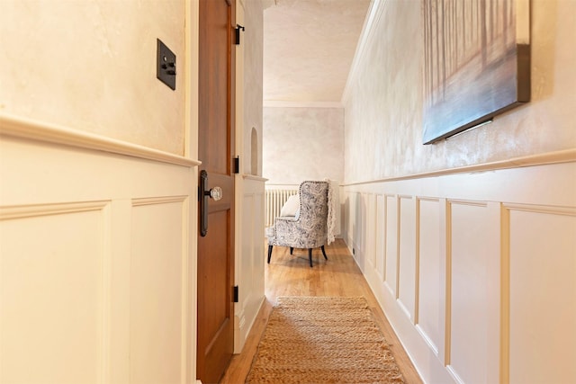 corridor featuring light wood-type flooring and ornamental molding