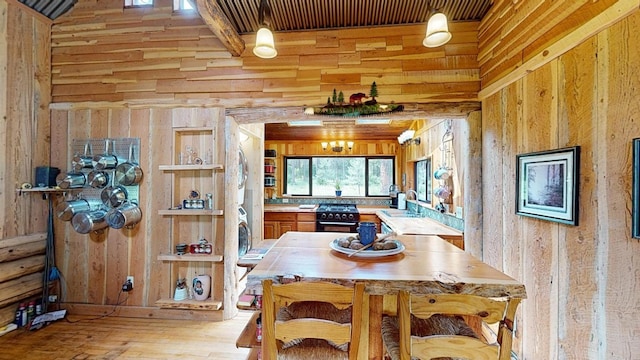 dining area with sink, light hardwood / wood-style floors, and wood walls