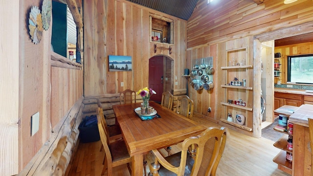 dining space with light hardwood / wood-style floors and wood walls