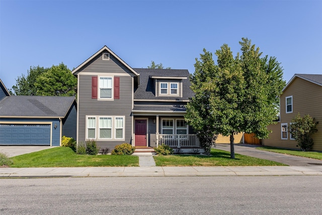 traditional-style home featuring a front lawn, a porch, concrete driveway, an attached garage, and a shingled roof