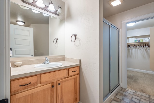 full bathroom with vanity, a shower stall, and a textured wall