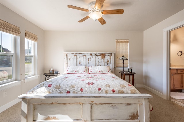 bedroom featuring ceiling fan, ensuite bath, baseboards, and light carpet