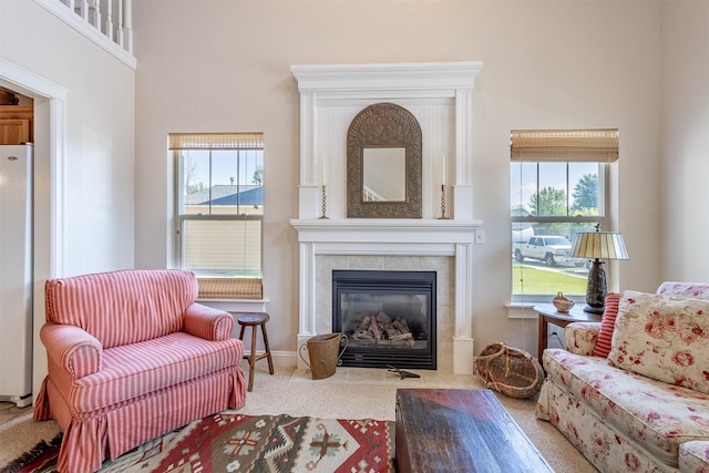 living area featuring carpet, a healthy amount of sunlight, and a tiled fireplace