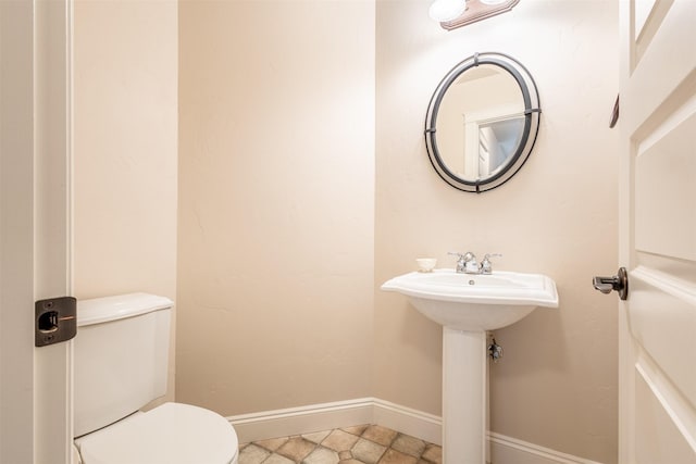 half bath with a sink, baseboards, and toilet