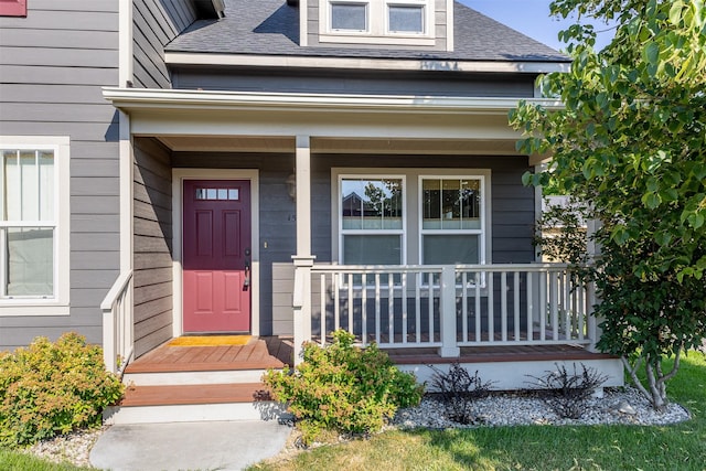 entrance to property with covered porch and a shingled roof