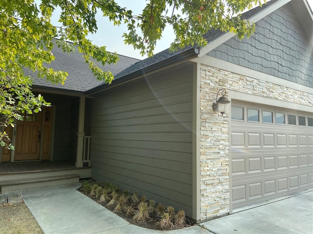 view of side of home with stone siding and roof with shingles