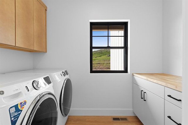 washroom featuring cabinets, washer and clothes dryer, and light hardwood / wood-style floors