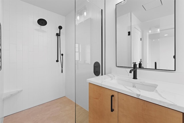 bathroom with tiled shower, vanity, and tile patterned flooring