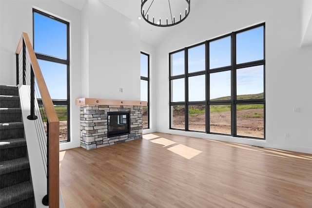 unfurnished living room featuring light wood-type flooring, a fireplace, a healthy amount of sunlight, and a towering ceiling